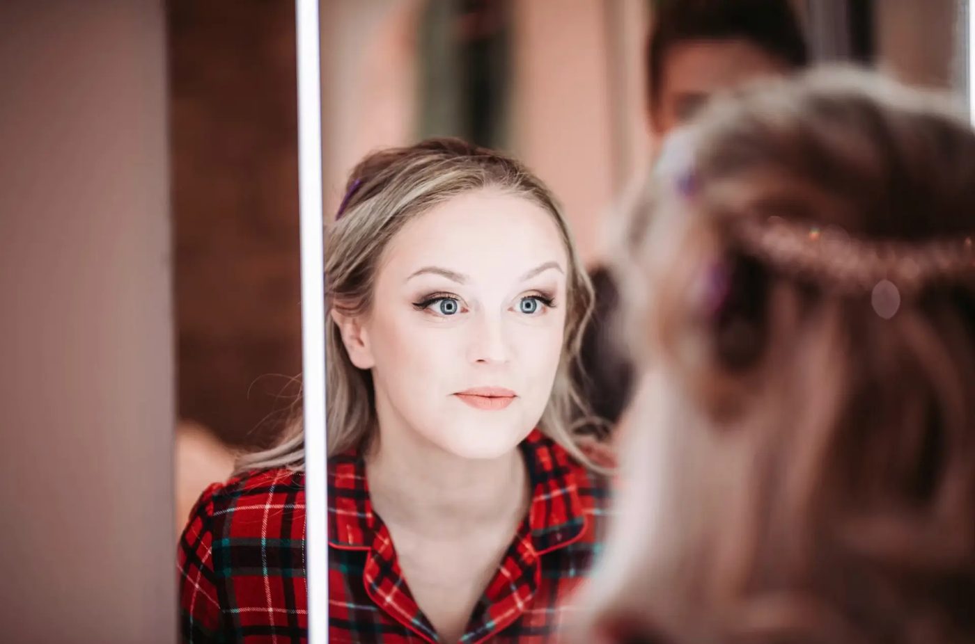 Bride checking her makeup in a lit mirror