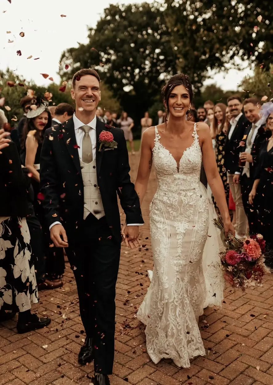 Bride and groom walking through confetti as guests applaud