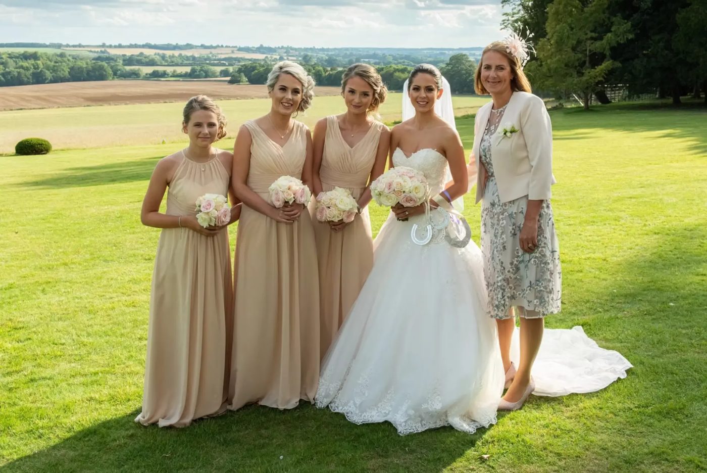 Bride, bridesmaids and mother of the bride on the lawn