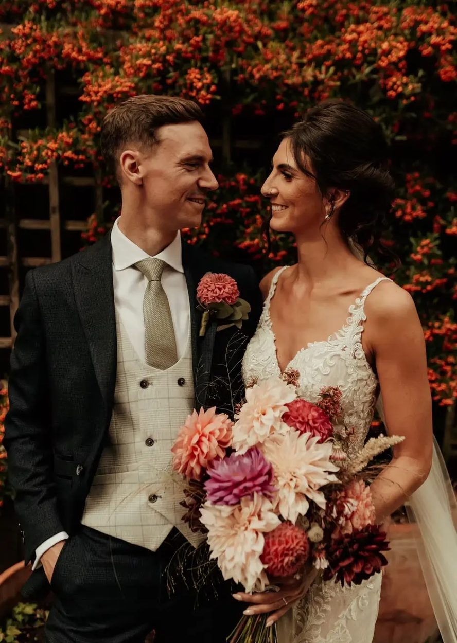 Bride and groom beside a berry-covered hedge