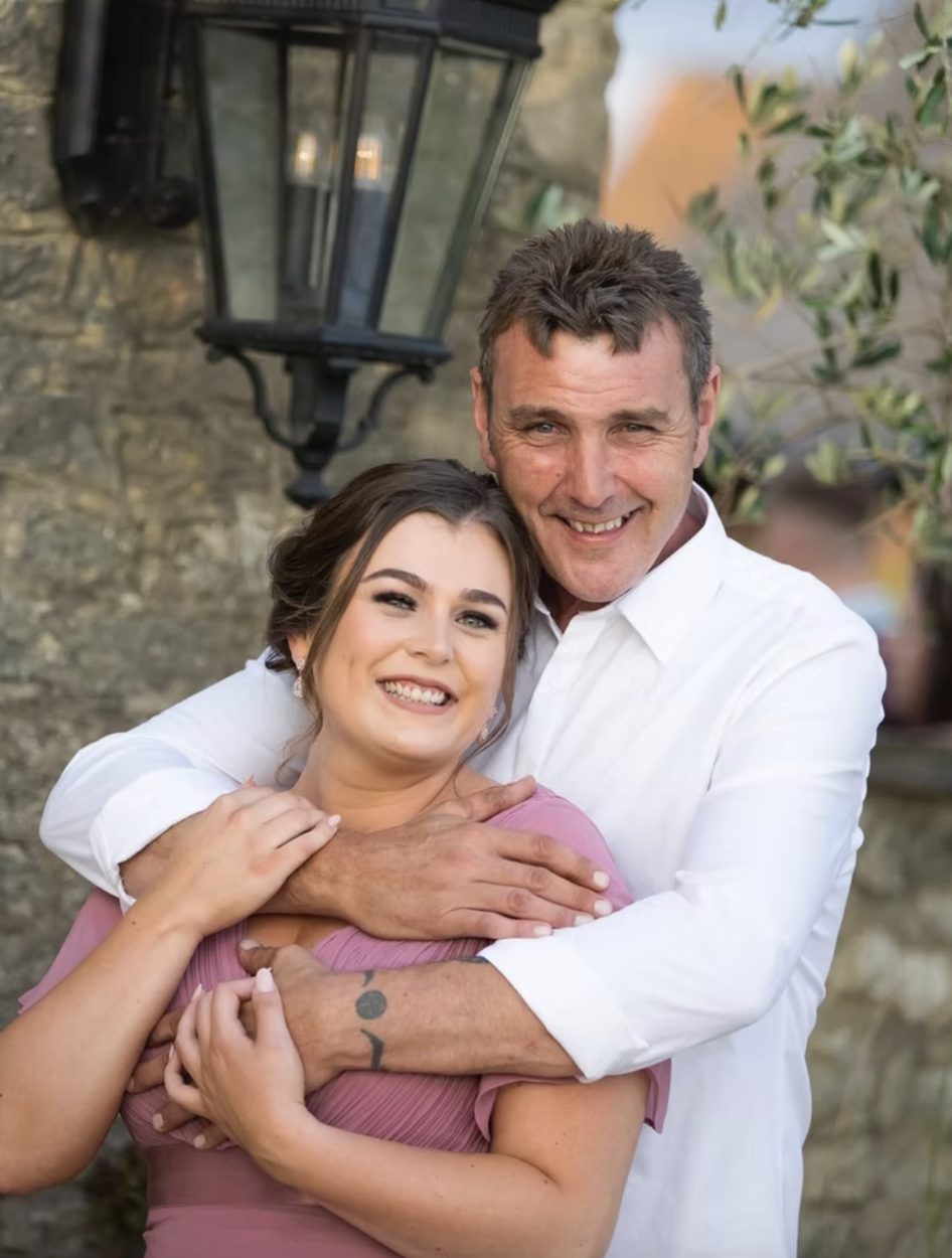 Couple embracing beside a stone wall